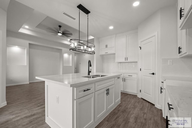 kitchen with white cabinets, a sink, visible vents, dark wood-style floors, and ceiling fan with notable chandelier