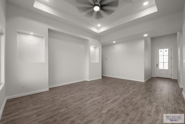 unfurnished room featuring a raised ceiling, recessed lighting, ceiling fan, and wood finished floors