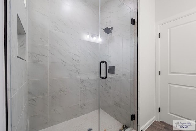 bathroom with a shower stall and wood finished floors