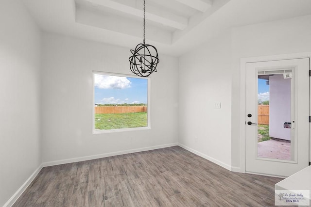 unfurnished dining area with beam ceiling, wood finished floors, a chandelier, and baseboards