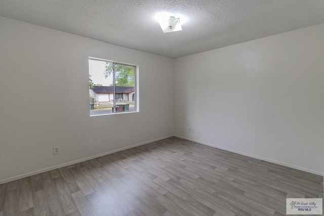 225 Chelo Dr, La Feria, TX 78559 - spare room with baseboards, wood finished floors, and a textured ceiling