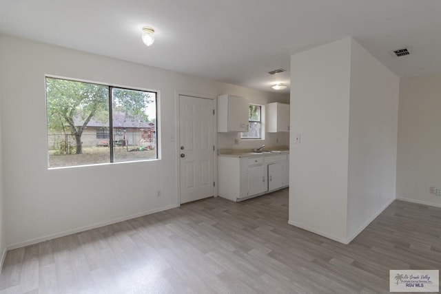 225 Chelo Dr, La Feria, TX 78559 - kitchen with visible vents, white cabinets, light wood-style flooring, and light countertops