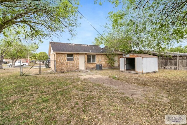 225 Chelo Dr, La Feria, TX 78559 - rear view of house with a gate, a storage unit, fence private yard, an outdoor structure, and a yard