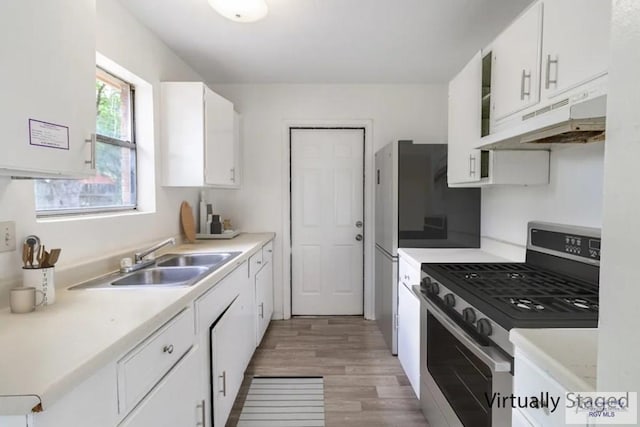 225 Chelo Dr, La Feria, TX 78559 - kitchen with a sink, light wood-style flooring, under cabinet range hood, white cabinets, and stainless steel range with gas cooktop