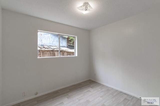 225 Chelo Dr, La Feria, TX 78559 - unfurnished room with baseboards, light wood-style flooring, and a textured ceiling