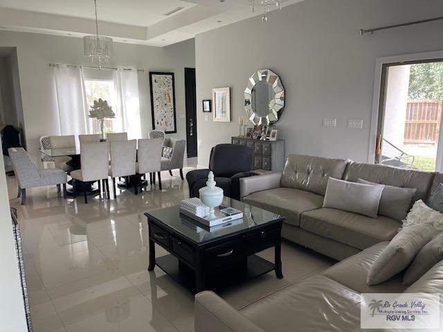 tiled living room with a notable chandelier