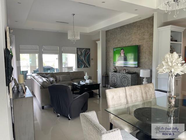 living room featuring light tile patterned floors, a tray ceiling, and a chandelier