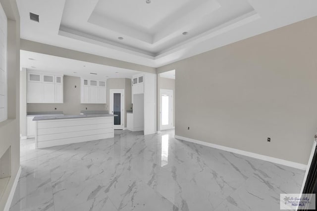 unfurnished living room featuring marble finish floor, a raised ceiling, visible vents, and baseboards