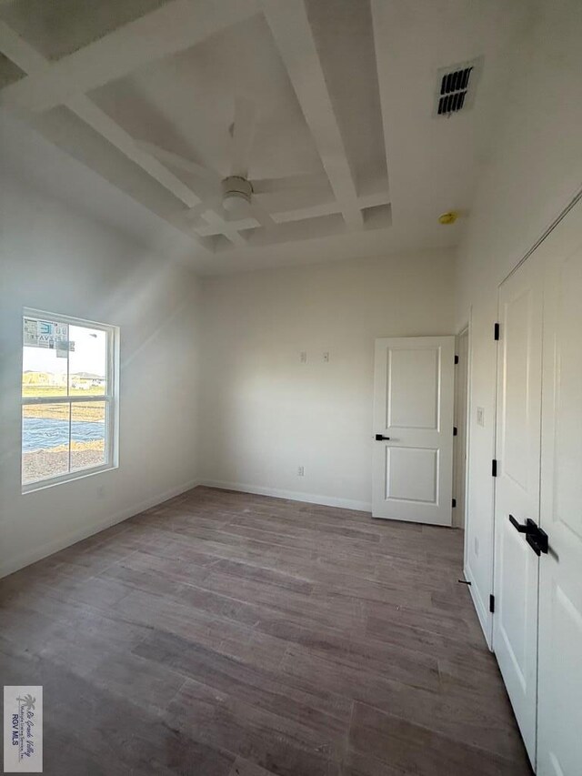 unfurnished room with beamed ceiling, coffered ceiling, wood finished floors, and a towering ceiling