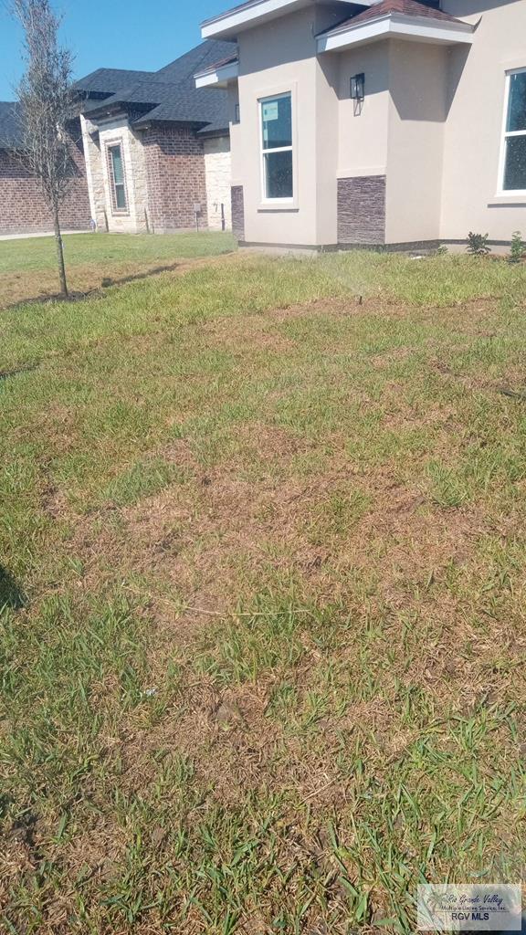 6214 Bentwood Dr, Harlingen, TX 78552 - rear view of house with stucco siding and a lawn