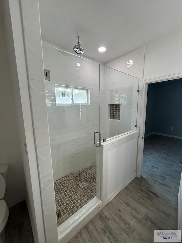 bathroom featuring hardwood / wood-style flooring, toilet, and walk in shower