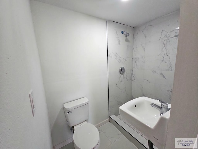 bathroom with tiled shower, sink, and toilet