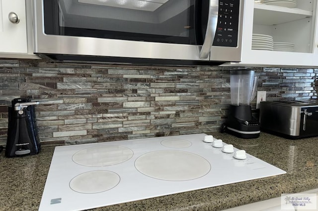 interior details with white electric cooktop, decorative backsplash, and stone countertops