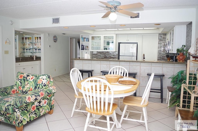 tiled dining room featuring ceiling fan, sink, and a textured ceiling