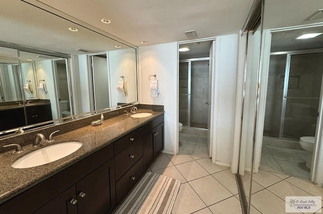 bathroom featuring toilet, vanity, tile patterned floors, and an enclosed shower