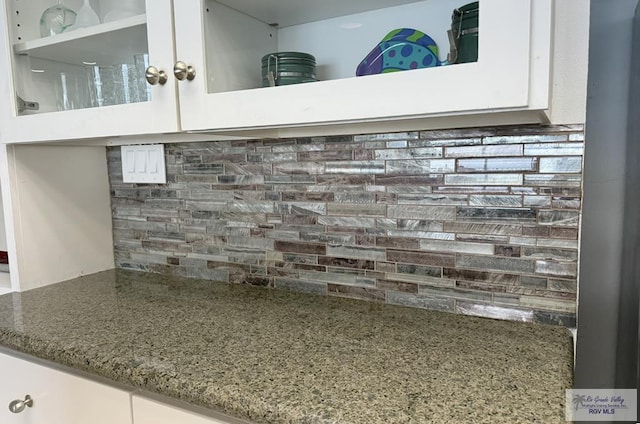 details featuring backsplash and white cabinetry