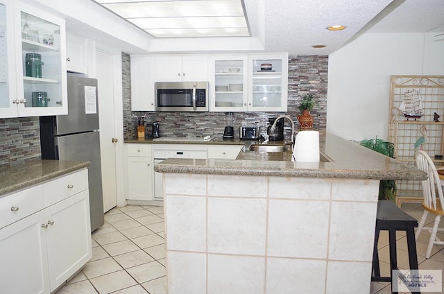 kitchen featuring decorative backsplash, stainless steel appliances, white cabinetry, and sink