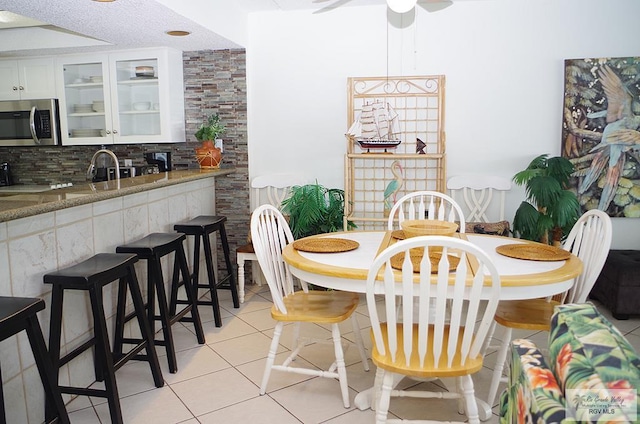 tiled dining space with a textured ceiling, ceiling fan, and sink