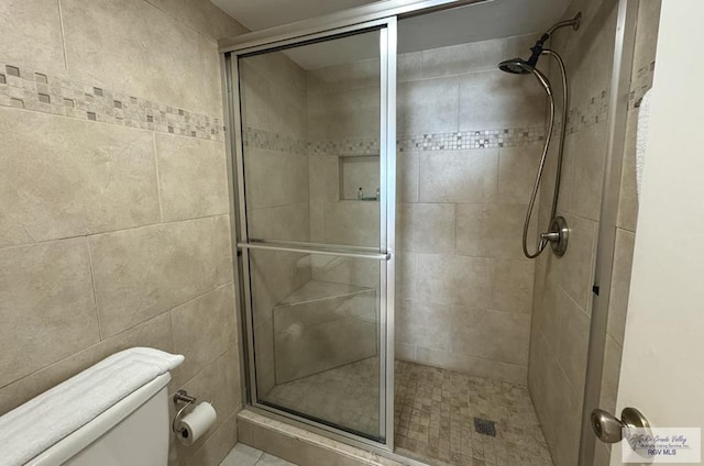 bathroom featuring toilet and a shower with door