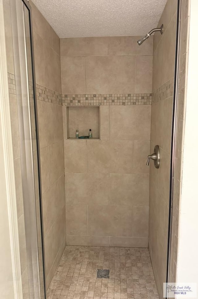 bathroom with tiled shower and a textured ceiling