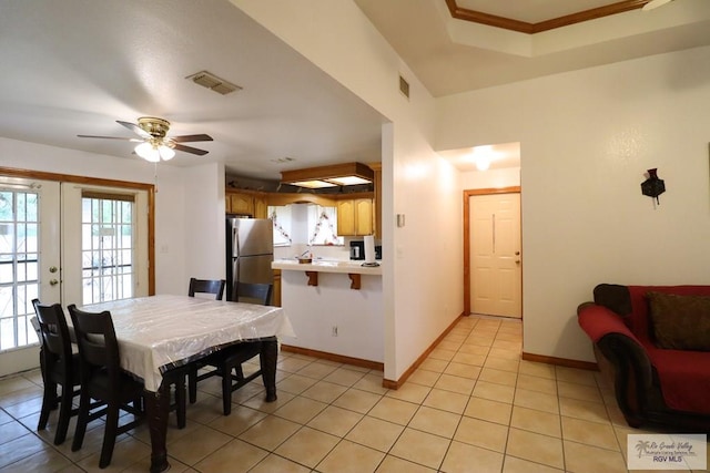 tiled dining space featuring ceiling fan, ornamental molding, and french doors