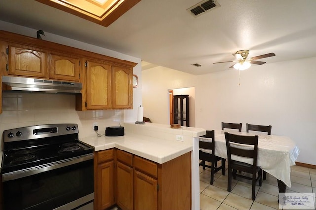 kitchen featuring backsplash, kitchen peninsula, light tile patterned flooring, ceiling fan, and electric range