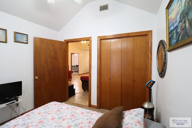 bedroom featuring vaulted ceiling, a closet, light tile patterned floors, and ceiling fan