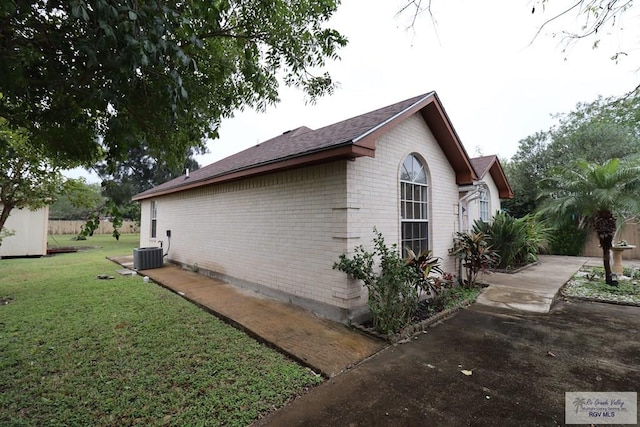 view of side of property featuring cooling unit and a yard