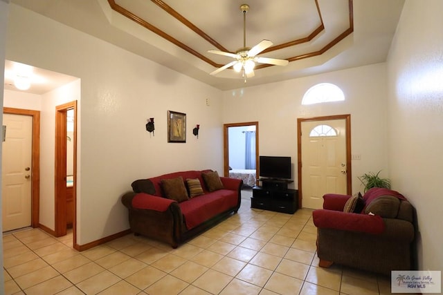 living room featuring ceiling fan, light tile patterned floors, and a raised ceiling