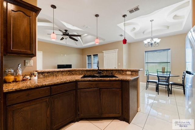 kitchen with ceiling fan with notable chandelier, a raised ceiling, light tile patterned floors, and sink