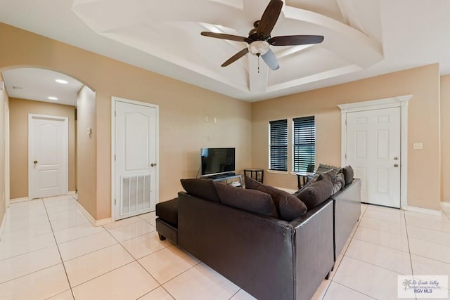 living room with a tray ceiling, ceiling fan, and light tile patterned flooring