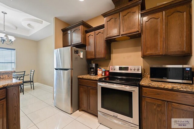 kitchen featuring light tile patterned floors, stainless steel appliances, dark stone counters, and a chandelier