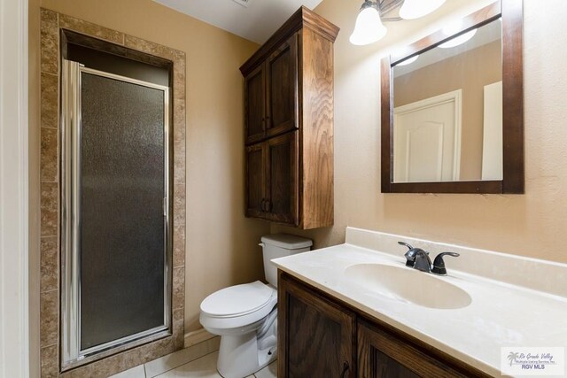 bathroom featuring tile patterned flooring, vanity, a shower with shower door, and toilet