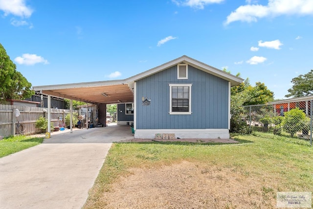 exterior space with a carport, concrete driveway, fence, and a front yard