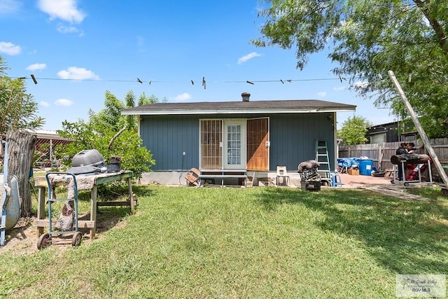 back of property with entry steps, a patio area, fence, and a lawn