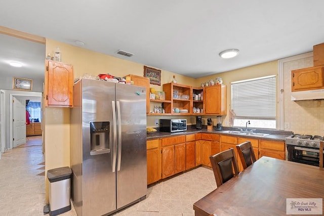 kitchen with dark countertops, visible vents, under cabinet range hood, appliances with stainless steel finishes, and a sink