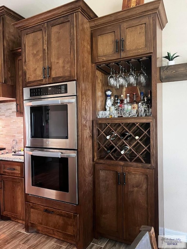 interior space featuring tasteful backsplash, baseboards, stainless steel double oven, and wood finished floors