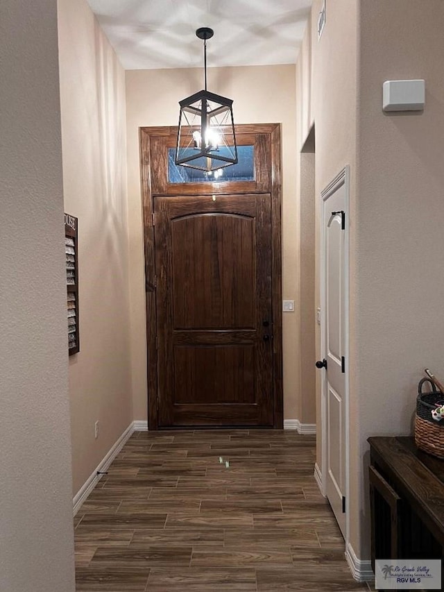 entryway with wood tiled floor, a notable chandelier, and baseboards