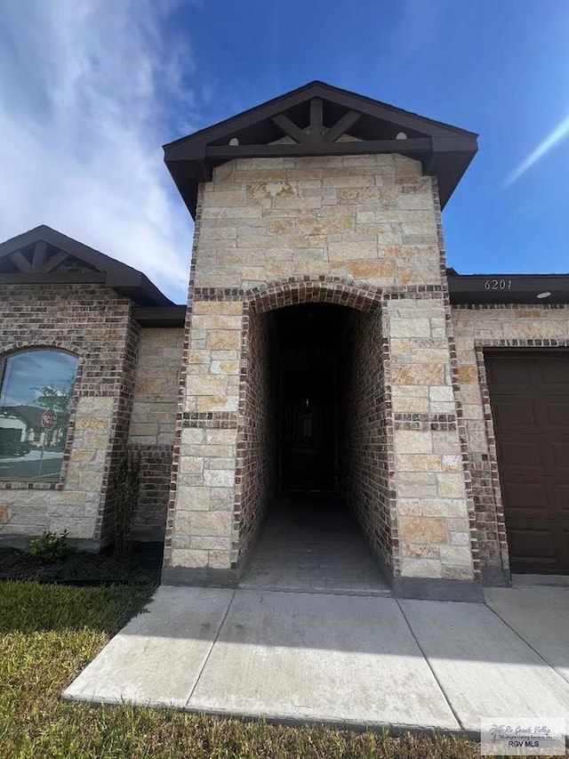 view of exterior entry with stone siding and brick siding