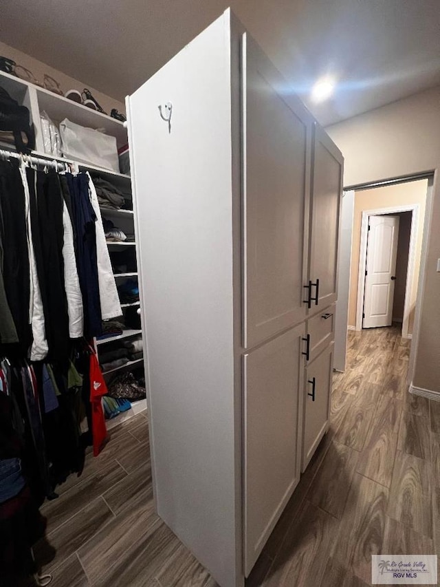 walk in closet with wood finished floors