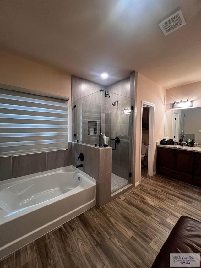 bathroom featuring a garden tub, visible vents, toilet, a stall shower, and wood finished floors