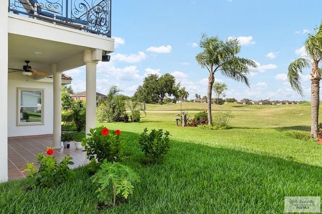 view of yard featuring a balcony and ceiling fan