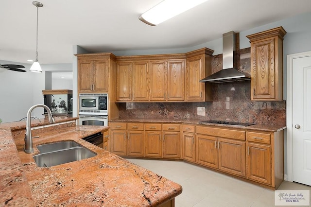 kitchen featuring pendant lighting, backsplash, wall chimney range hood, sink, and appliances with stainless steel finishes