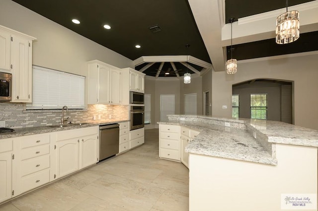 1101 Chico Cir, Harlingen, TX 78552 - kitchen with a sink, decorative backsplash, arched walkways, white cabinets, and appliances with stainless steel finishes