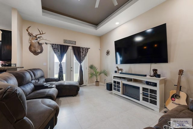 living room featuring french doors, a tray ceiling, and ceiling fan