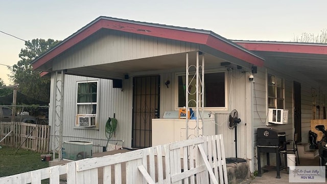 view of front of home with cooling unit, washer / clothes dryer, and fence