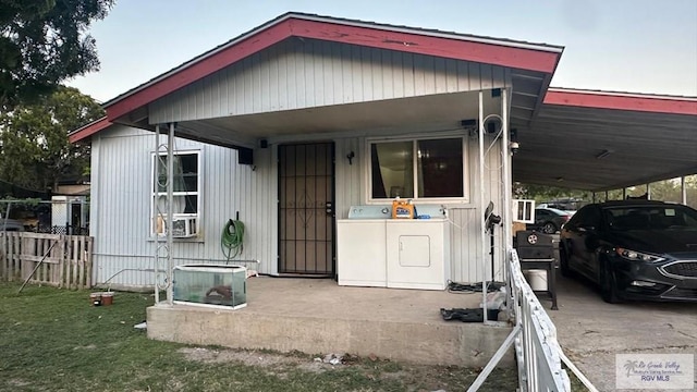 view of front of home featuring an attached carport, washer / dryer, and fence