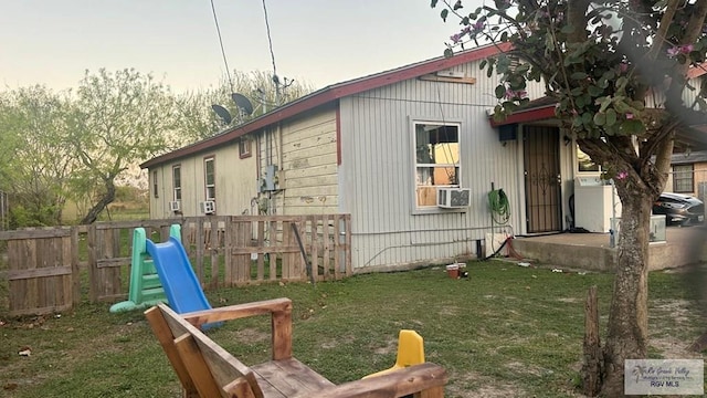 view of side of property featuring washer / dryer, cooling unit, a yard, and fence