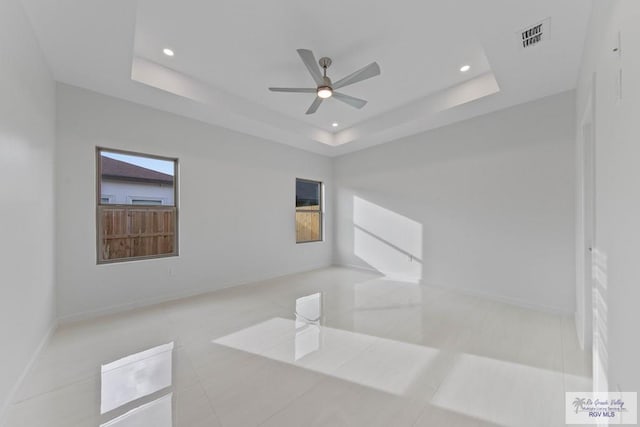 spare room featuring a tray ceiling, recessed lighting, visible vents, and baseboards