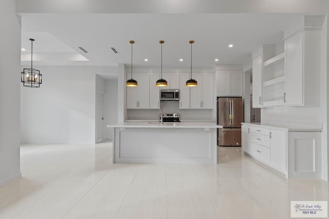 kitchen featuring stainless steel appliances, white cabinetry, light countertops, an island with sink, and decorative light fixtures